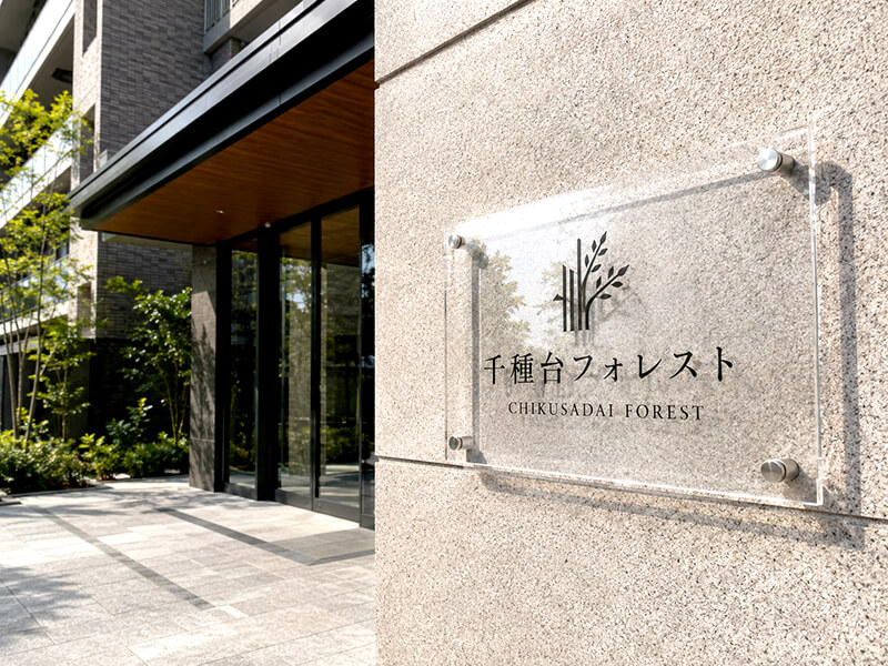 マンションエントランスに掲げられた透明アクリルの建物銘板。上品で重厚感のある事例