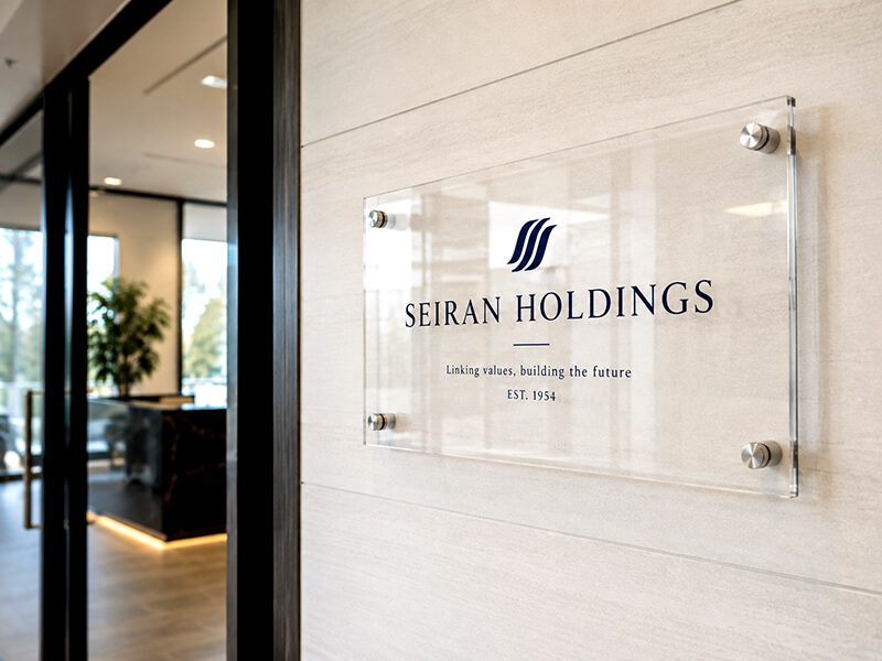 透明アクリルの会社銘板が掲げられたオフィスエントランス。信頼感のある事例