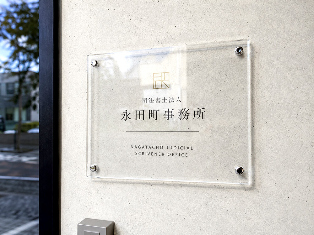 壁に化粧ビスで直付けされたアクリル看板