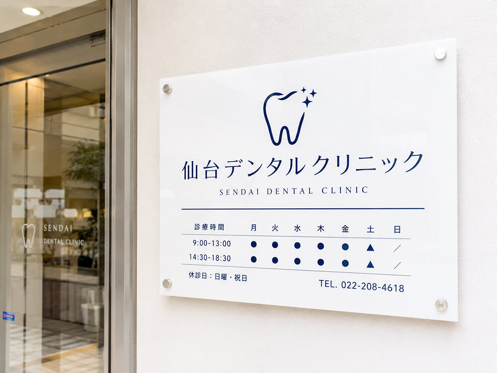白アクリルに紺文字で仕上げた歯科クリニックの看板。清潔感のある事例
