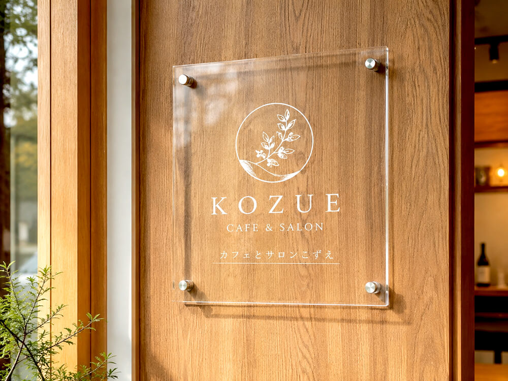 木目の壁に浮かせて取り付けられた透明アクリル看板。背景になじみつつロゴが上品に見える事例
