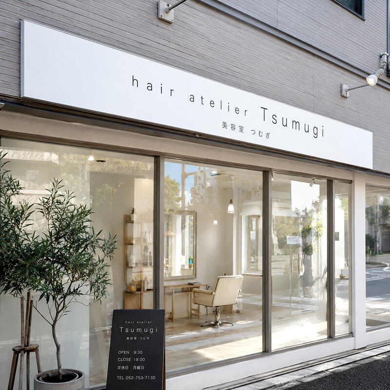 hair atelier Tsumugiの横長プレート看板。美容室のファサードに設置
