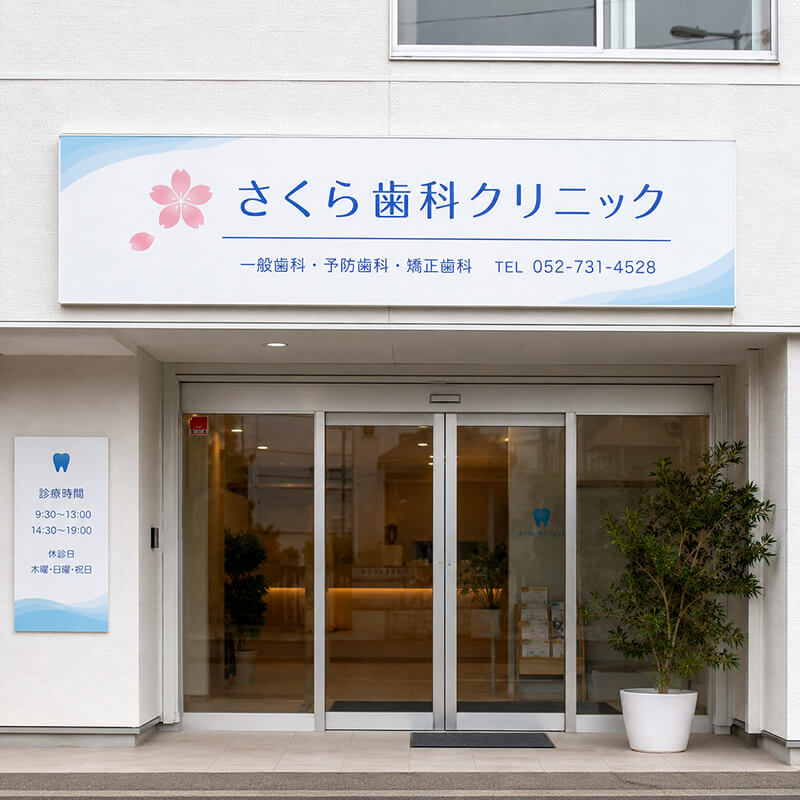 さくら歯科クリニックのプレート看板。淡いブルーと桜マーク