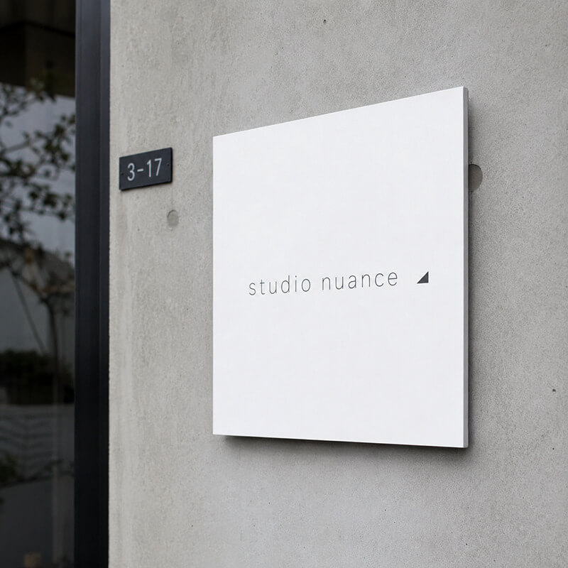 studio nuanceのプレート看板。コンクリート壁にミニマルな白い看板
