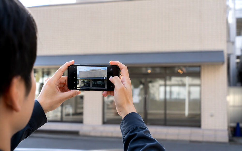 スマホで店舗の壁を撮影しているシーン